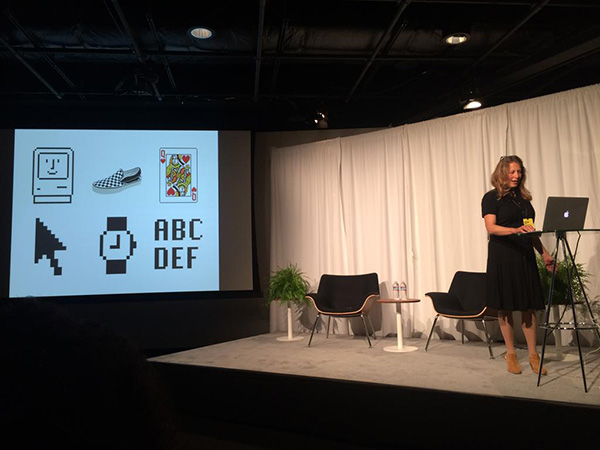 Susan Kare on stage, next to a projector showing some of her designs.